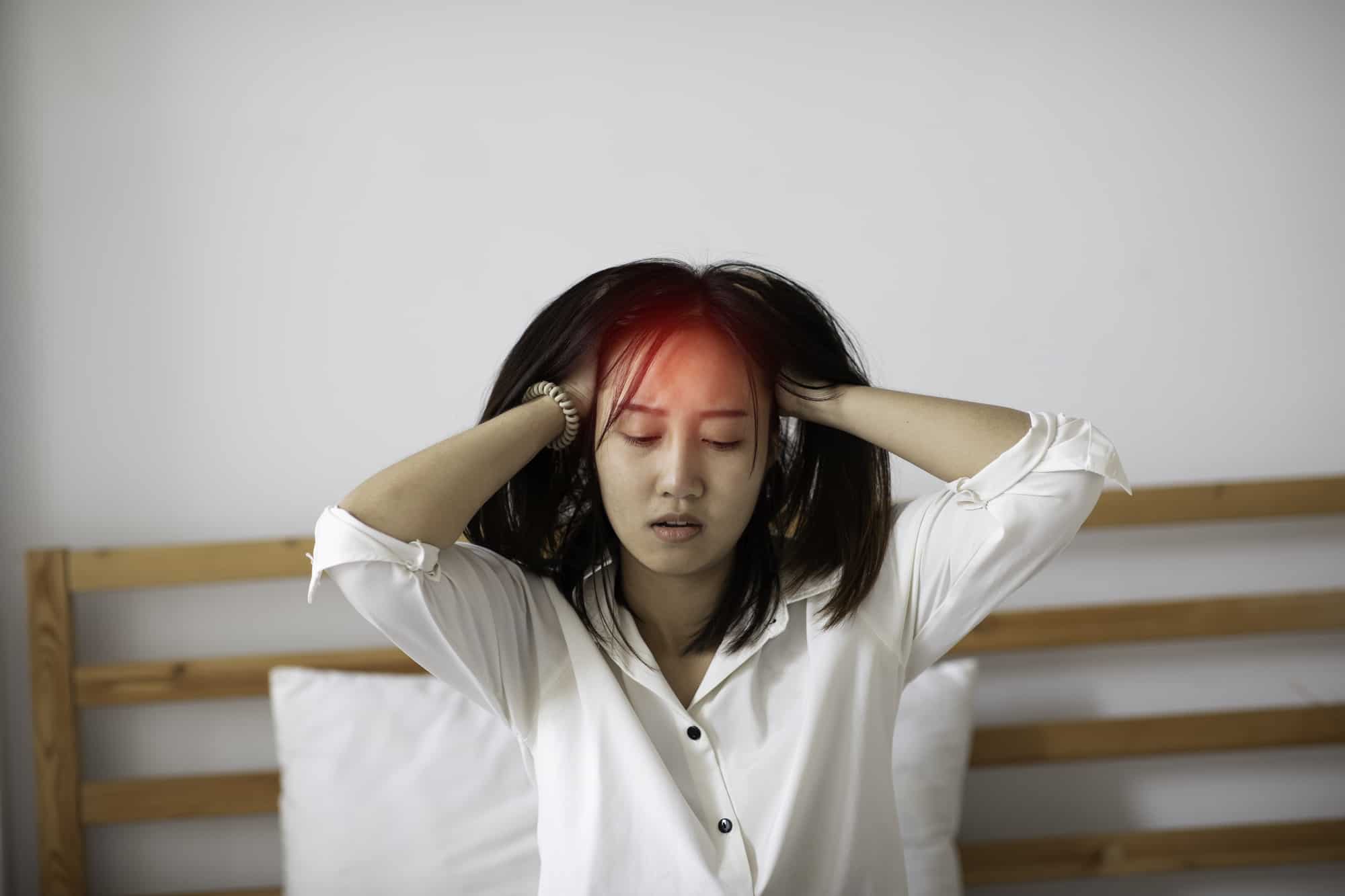 Asian young Woman has a Migraine and headache after wake up in the morning